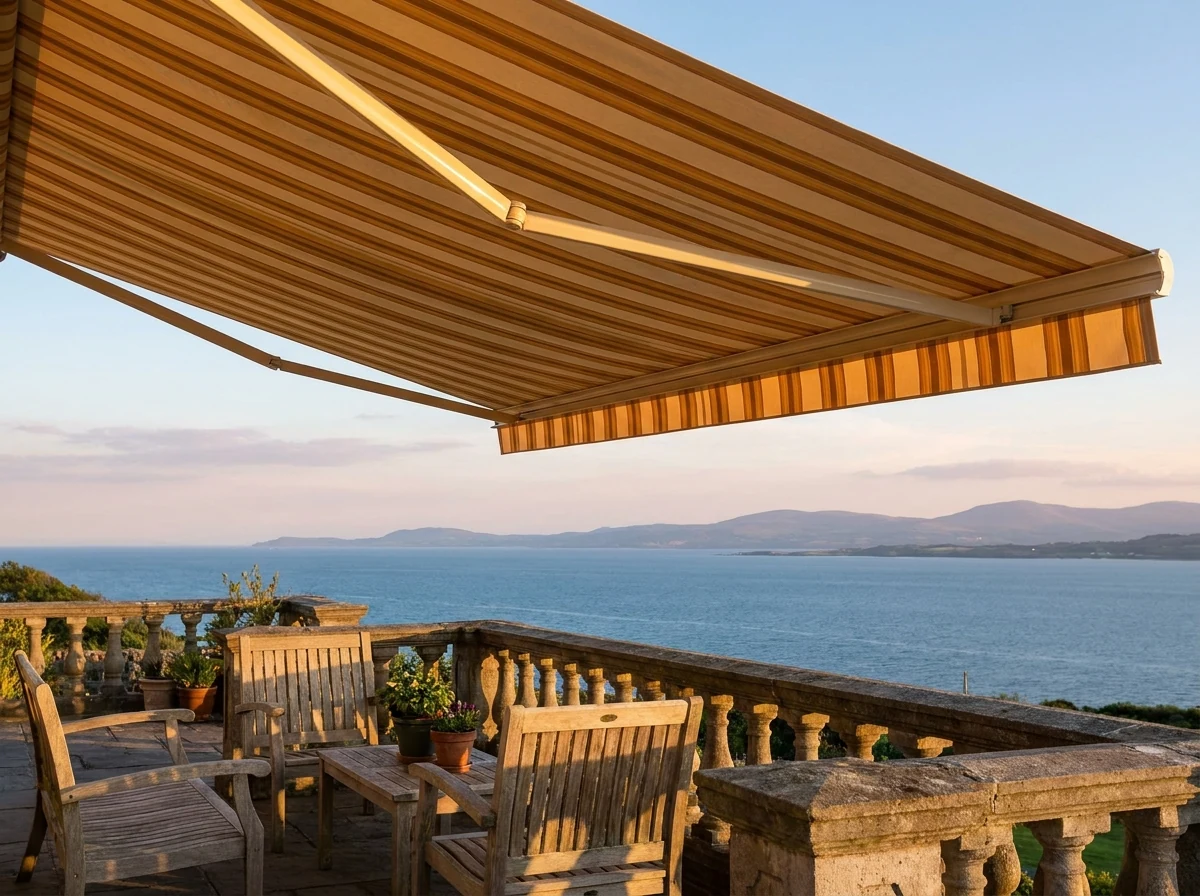Retractable folding-arm awning extended over a Bantry Bay terrace with evening light over the Atlantic Ocean
